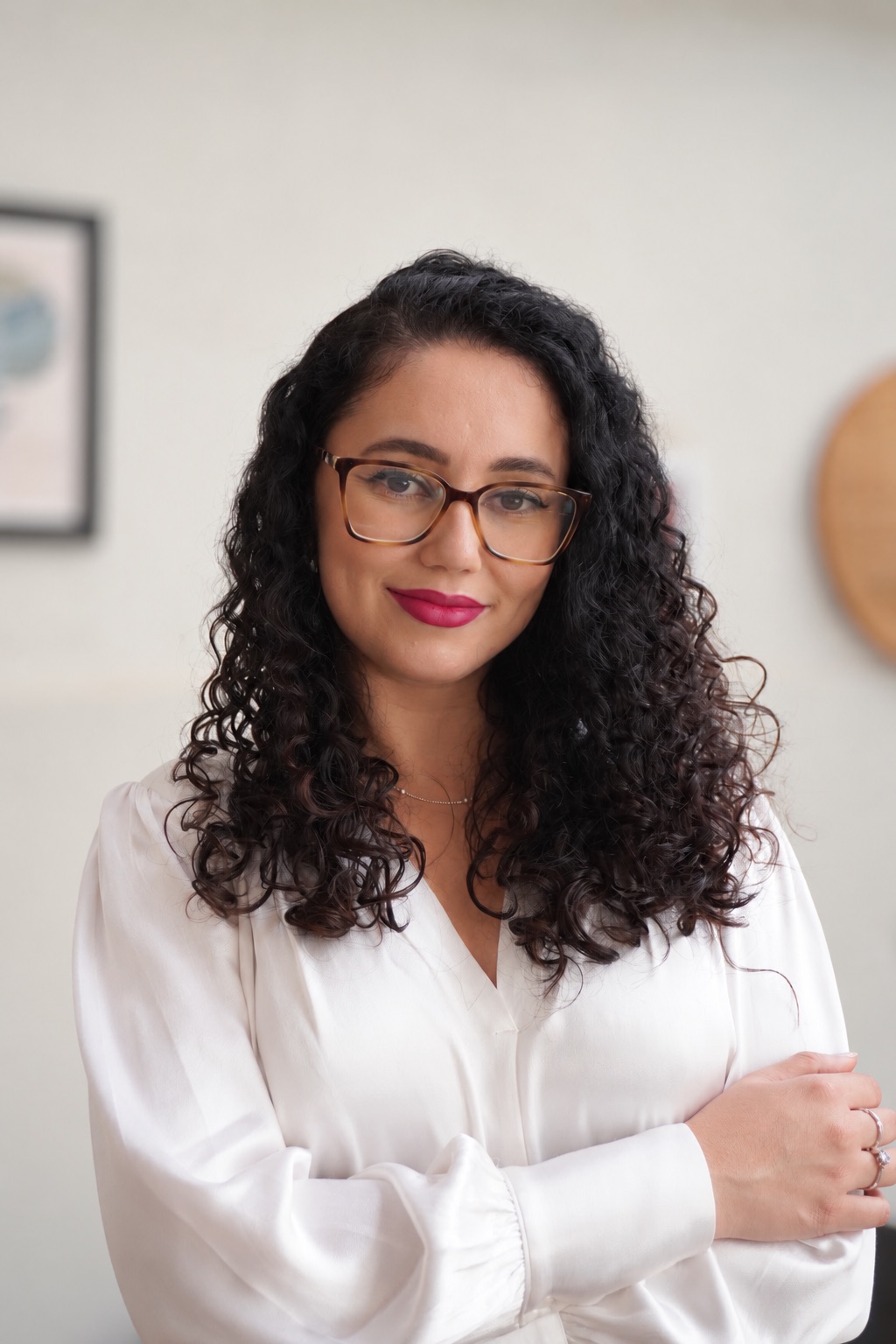 Retrato de Mayara Dias sorrindo, com os braços cruzados